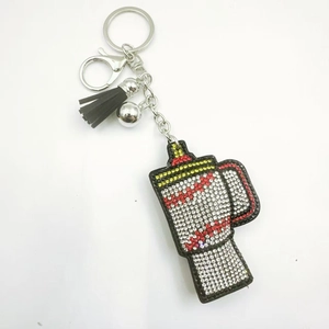 Detail of a sparkling rhinestone studded keychain in a tumbler cup shape with black tassel