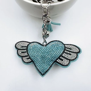 Detailed macro shot of light blue rhinestone heart keychain with wings and tassel detail
