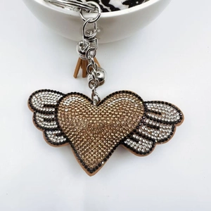 Detail of a sparkling heart wing keychain with champagne rhinestones and leather tassel