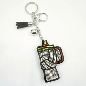Detail of glittery cup keychain with black and white rhinestones and a black leather tassel
