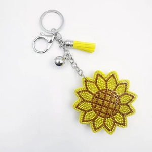 Porte-clés tournesol en strass avec pompon jaune et fermoir mousqueton sur fond blanc éclatant