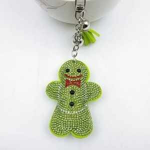 Close-up of green gingerbread man keychain with rhinestones, silver bells and a silk tassel