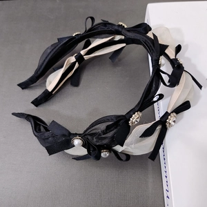 Elegant mesh bow headbands in black and beige with pearl accents in a top-down view