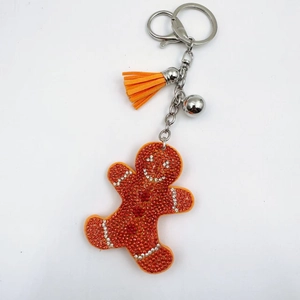 Macro detail of gingerbread man keychain with orange rhinestones and a suede tassel