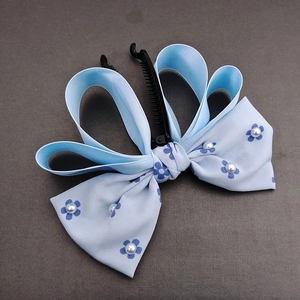 Detailed macro view of blue bow banana hair clip with satin ribbon and white pearls