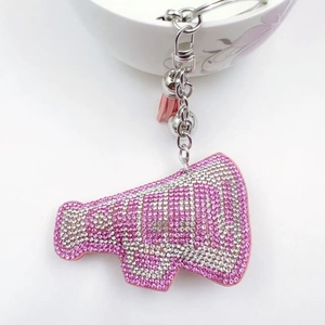 Detailed macro view of pink rhinestone megaphone keychain with tassel and bell