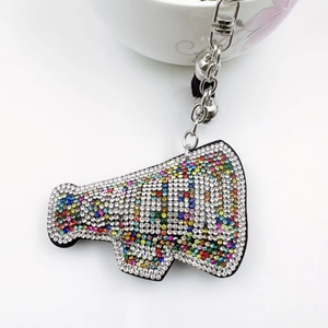 Macro detail of crystal megaphone keychain with MAMA lettering and silver bells