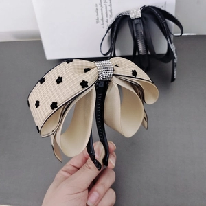 Detail of banana hair clip featuring beige ribbon with black floral print and sparkling rhinestones