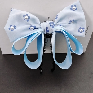 Elegant light blue bow banana clip with pearl accents and dark blue floral patterns