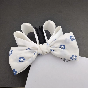Elegant white satin bow hair clip with blue flower patterns and centered faux pearls