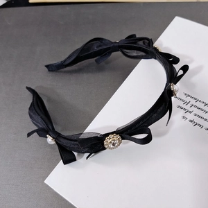 Close-up of elegant black mesh bow headband with delicate pearls and rhinestone centerpiece