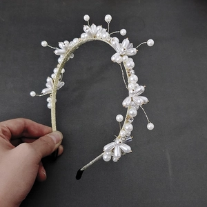 Close-up of golden metal headband featuring white pearls and sparkling crystal flowers