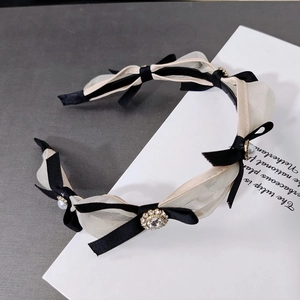 Detail of elegant mesh bow headband featuring white faux pearls and rhinestone metal accents