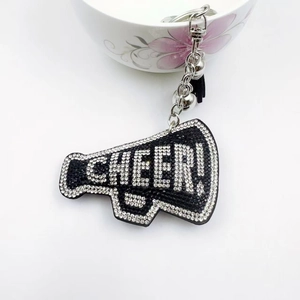 Close-up of a rhinestone megaphone keychain with CHEER text and black leather tassel