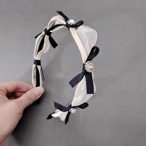 Detail of elegant mesh bow headband featuring pearls and rhinestone flower center