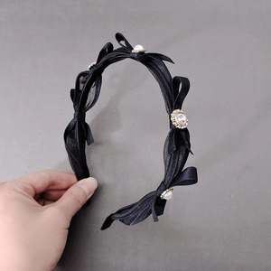 Detail view of the layered black mesh bow headband featuring elegant pearls and rhinestones