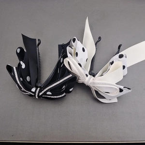 Detail of black and beige polka dot bow banana hair clips with sparkling rhinestone trim