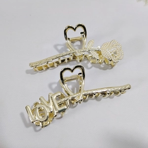 Detail of gold metal claw clips featuring rose floral and LOVE letter cutouts