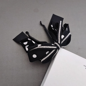 Detail of polka dot bow banana clip featuring sparkling rhinestone edges and plastic teeth