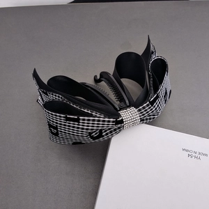 Detail of banana hair clip with black and white plaid bow and sparkling rhinestone center