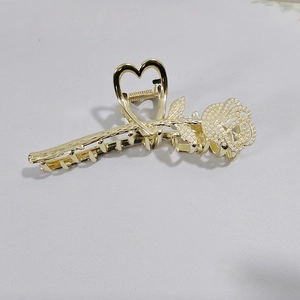 Detailed view of large gold shark clip with rose pearl inlay and heart cutout handle