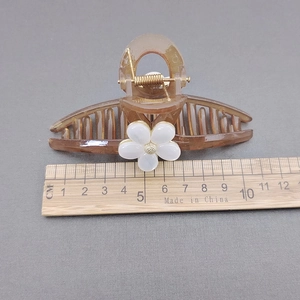 Detailansicht der Bernstein-Haarklammer mit weißer Blume und Zentimeter-Maßstab