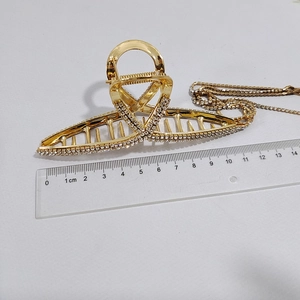 Golden metal hair claw clip with rhinestones measured at 11.5cm length on white backdrop