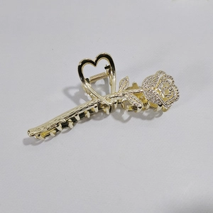 Close-up of golden rose hair claw clip with heart handle and sparkling rhinestones