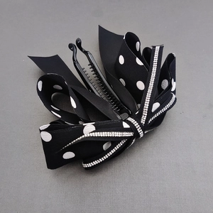 Close-up of black polka dot ribbon banana clip with sparkling rhinestone center detail