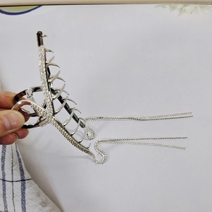 Detailed close-up of a silver hair claw clip with rhinestones and long tassel chains