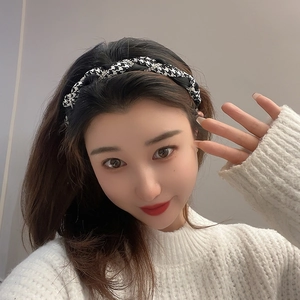 Front view of model wearing a black and white houndstooth headband with subtle sequins
