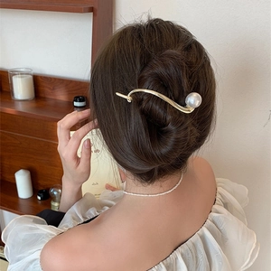 Dettaglio di un fermaglio per capelli dorato curvo con una grande perla sui capelli