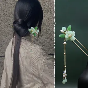Dettaglio macro del fermaglio per capelli con peonia verde e lunghe nappe
