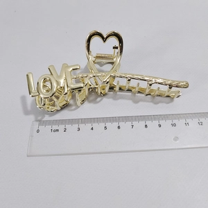 Detail view of 10cm gold LOVE letter metal hair claw clip showing size with ruler