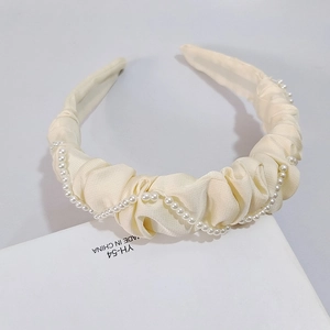 Détail d'un serre-tête en satin froncé crème orné de perles artificielles blanches