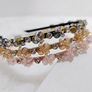 Macro shot of three hand-woven crystal beaded headbands in black, brown and pink