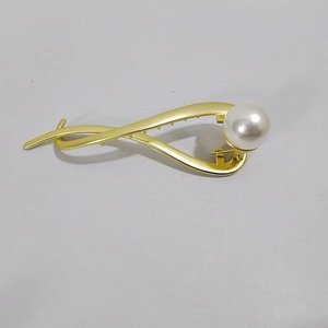 Dettaglio del fermaglio per capelli in oro con design a croce e perla bianca lucida