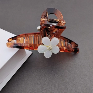 Detailansicht einer großen Haarklammer in Bernsteinoptik mit weißen Blumenmotiven