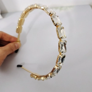 Dettaglio del cerchietto in metallo dorato con strass rettangolari e montatura a quattro griffe
