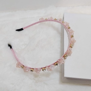 Detailed view of hand-woven crystal beads and pink satin headband with floral rhinestones