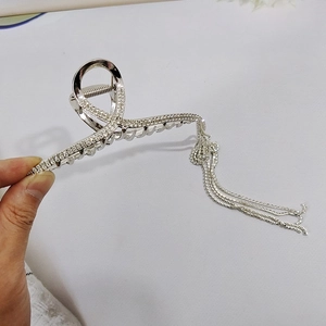 Detailed close-up of a silver hair claw clip with luxurious sparkling rhinestone tassels