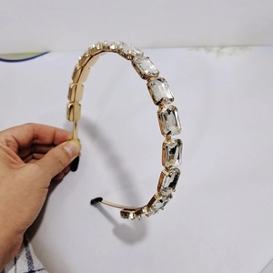 Dettaglio macro di cerchietto lussuoso dorato con grandi cristalli e strass rettangolari