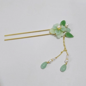 Dettaglio di forcina vintage con peonia verde, perle bianche e nappe dorate eleganti