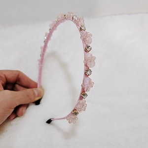 Detail of pink crystal rhinestones and resin flowers on a silk woven headband