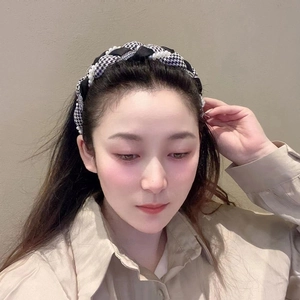 Detail of houndstooth braided headband featuring white pearls and elegant twist design