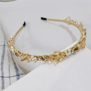 Close-up of elegant rhinestone headband with amber crystals and small pearls on gold wire