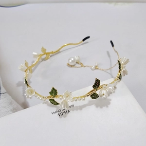 Détail d'un serre-tête doré avec muguet blanc et breloque en perle suspendue élégante