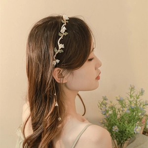 Gros plan sur un serre-tête floral avec fleurs blanches et pendentif métallique