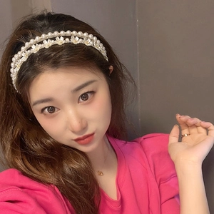 Détail d'un serre-tête double rangée de perles avec fleurs blanches sur haut rose