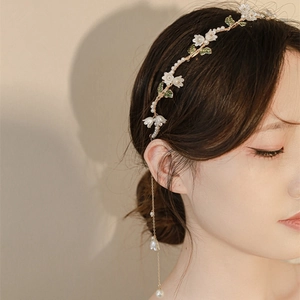 Serre-tête élégant aux fleurs de muguet et perles porté par un mannequin en gros plan